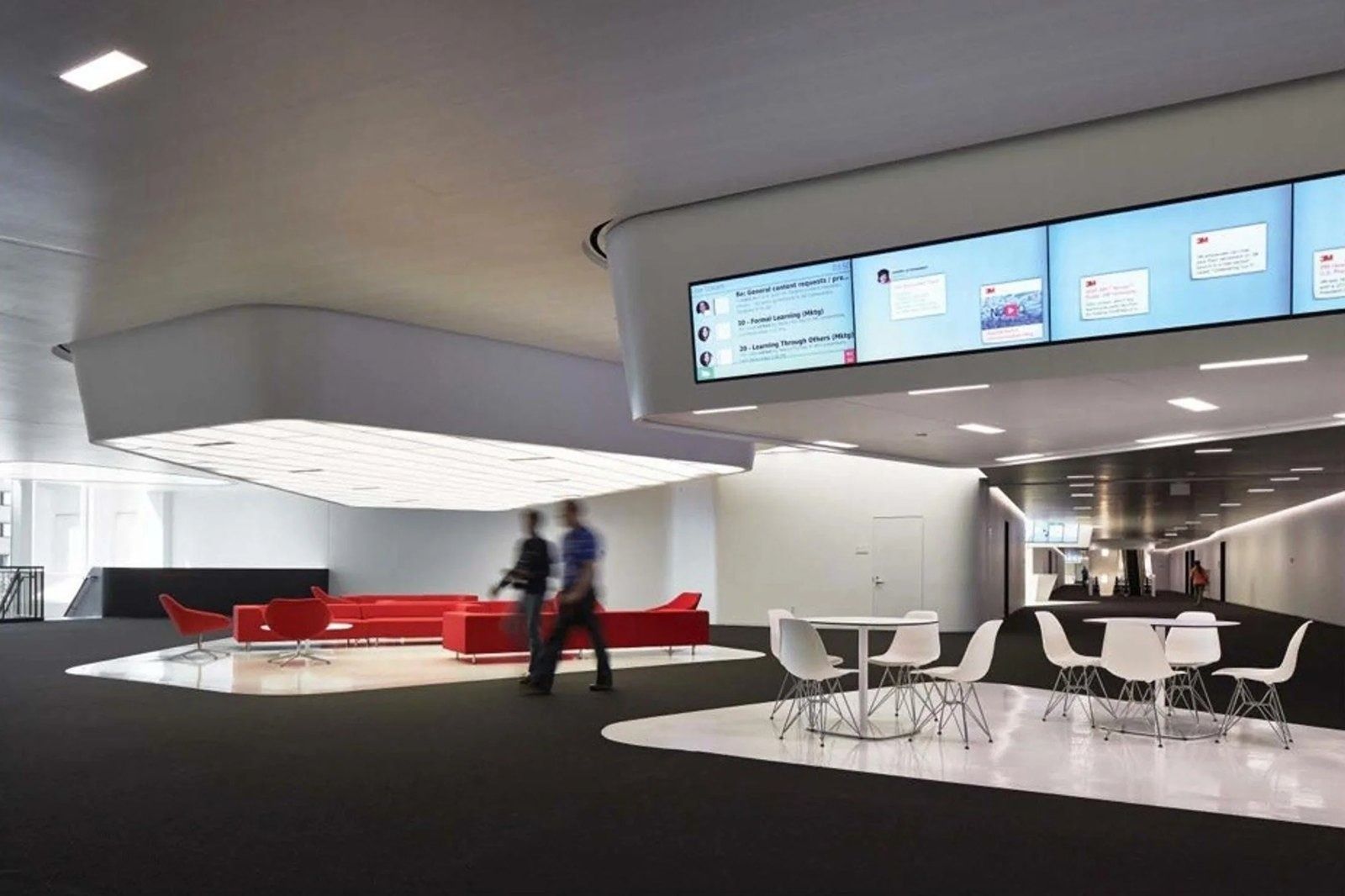 3M: Lounge with red sofas under screens