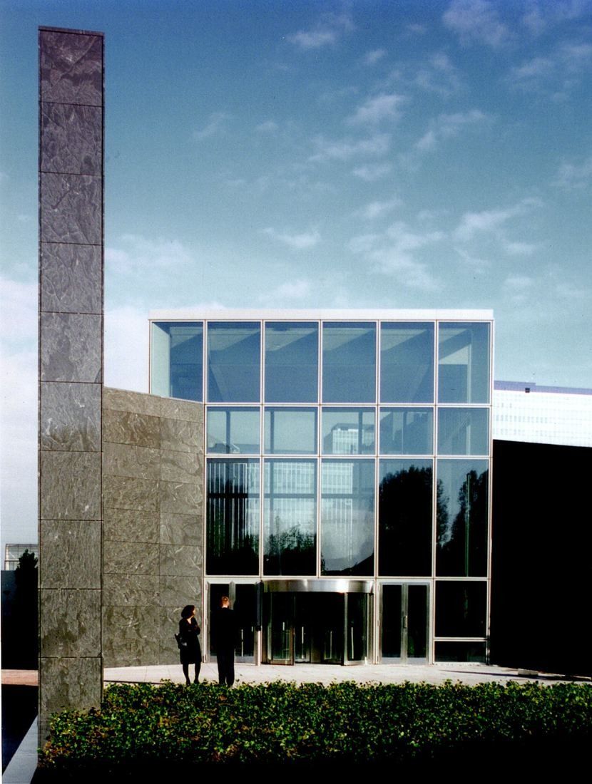 ABN AMRO: Glass box entrance between a stone wall and a dark building
