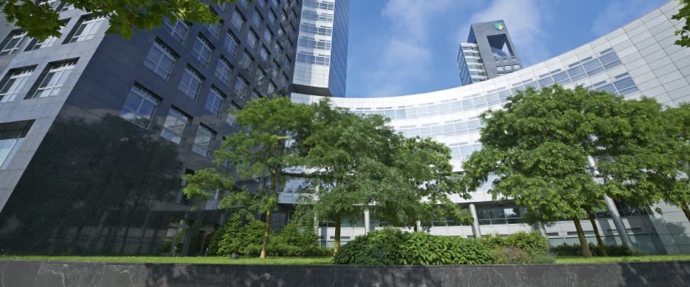 ABN AMRO: Green trees in front of curved glass office facades