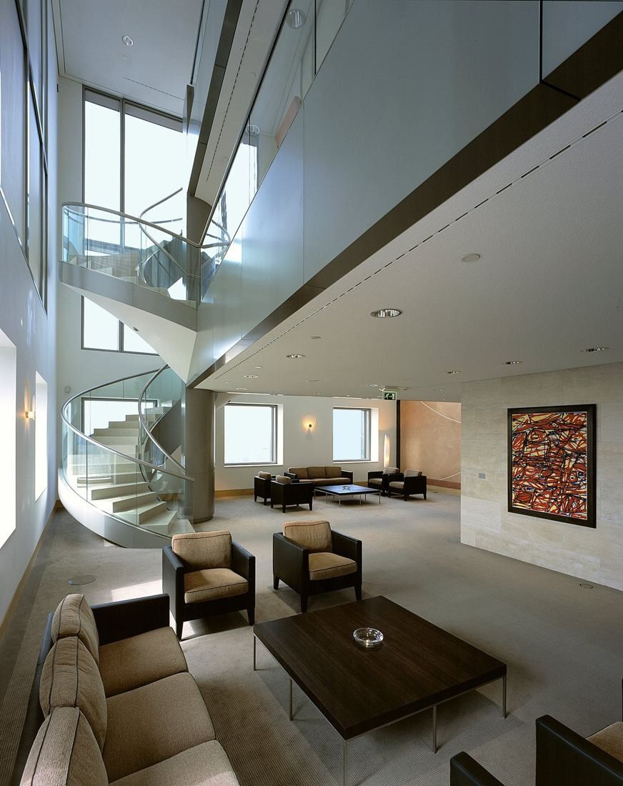 ABN AMRO: Lounge with sofas and a spiral staircase in a tall white space