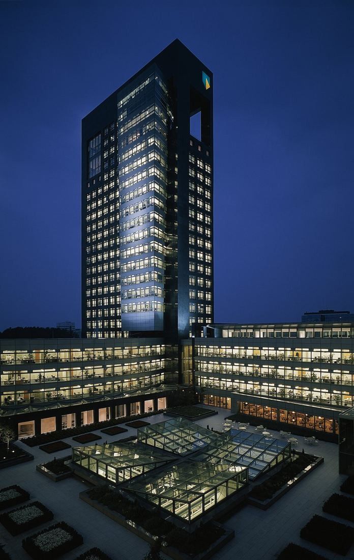 ABN AMRO: Tower and lit office wings around a courtyard at dusk