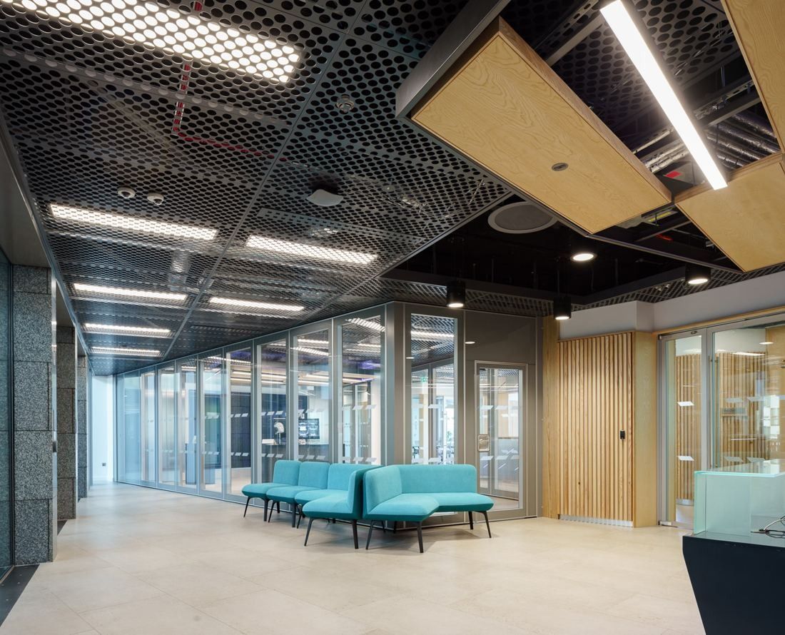 Accenture: Corridor with turquoise sofas, open-mesh ceiling and glass-fronted rooms
