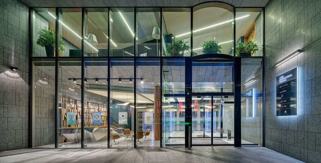 Accenture: Glass entrance enclosure seen from outside, with plants above and the lobby visible inside