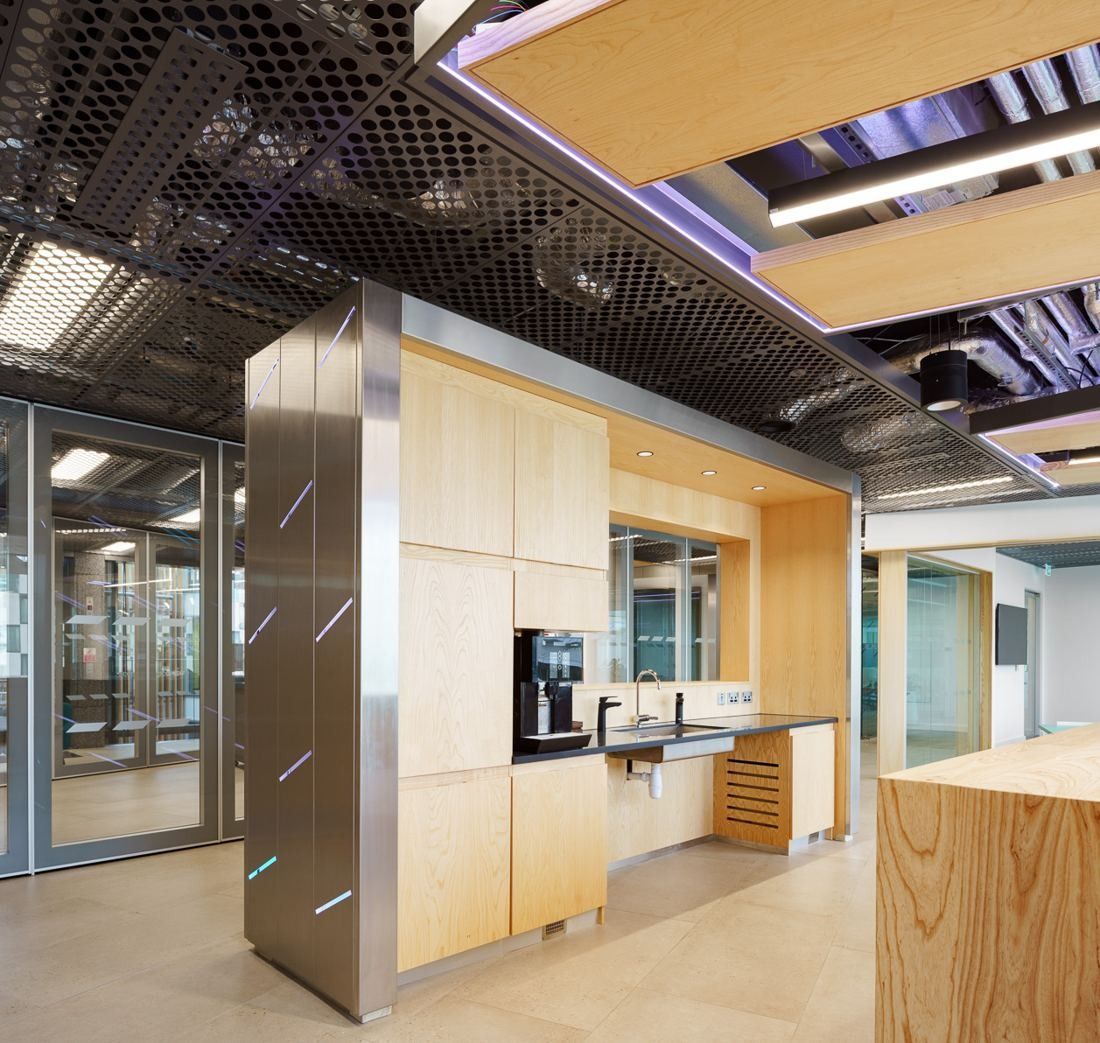 Accenture: Kitchen point with oak cabinetry and stainless steel panels under a suspended wooden ceiling