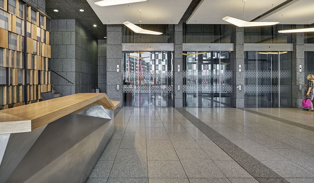 Accenture: Lobby with a faceted stainless steel and oak desk, angular pendant lights and glass lift doors