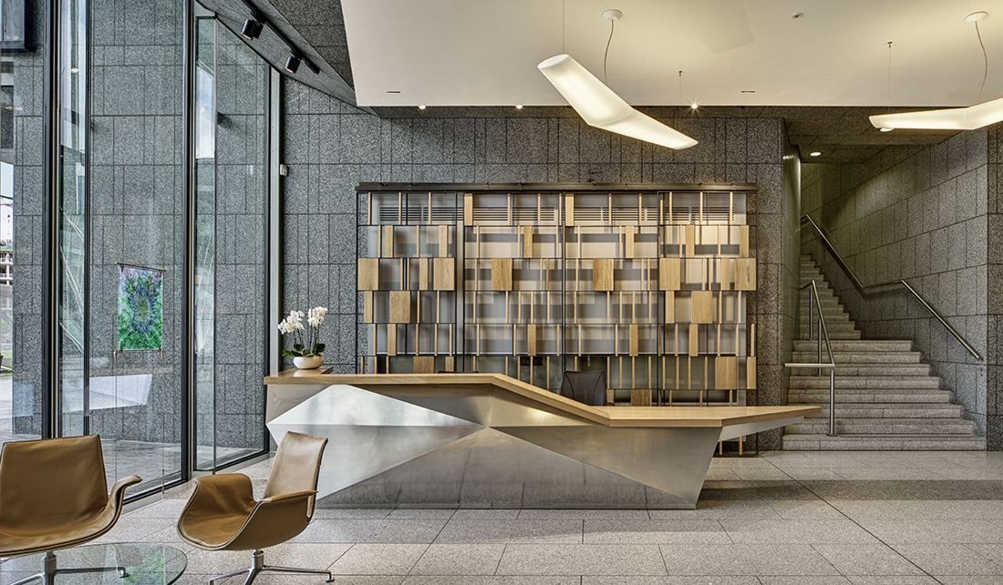 Accenture: Lobby with a sculpted oak and stainless steel reception desk, grey stone walls and a staircase