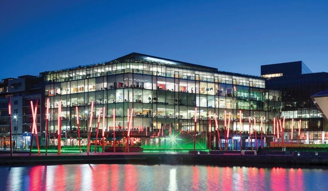 Accenture: Office building glowing at night with red light poles and green lights along the dock