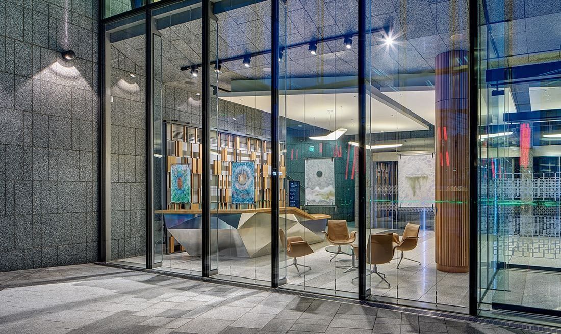 Accenture: Waiting area with armchairs behind a full-height glass wall set in grey stone
