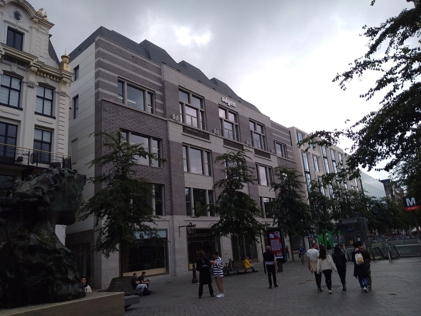 Adyen: Grey stone building on a pedestrian street with people walking