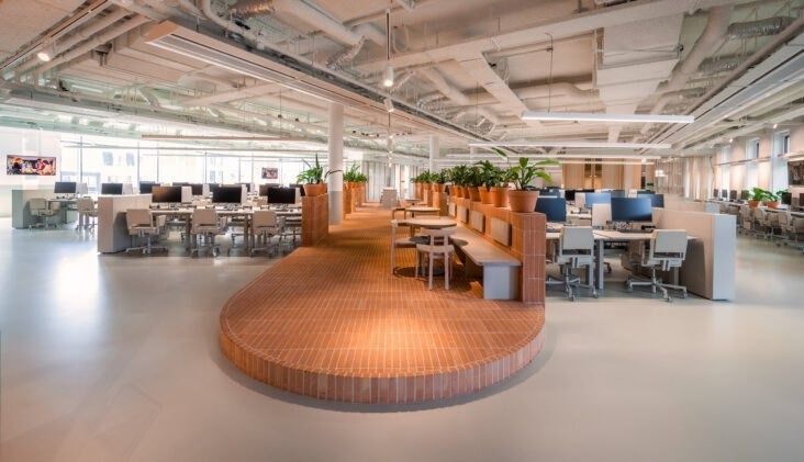 Adyen: Large open office floor with desks around a raised curved wooden platform