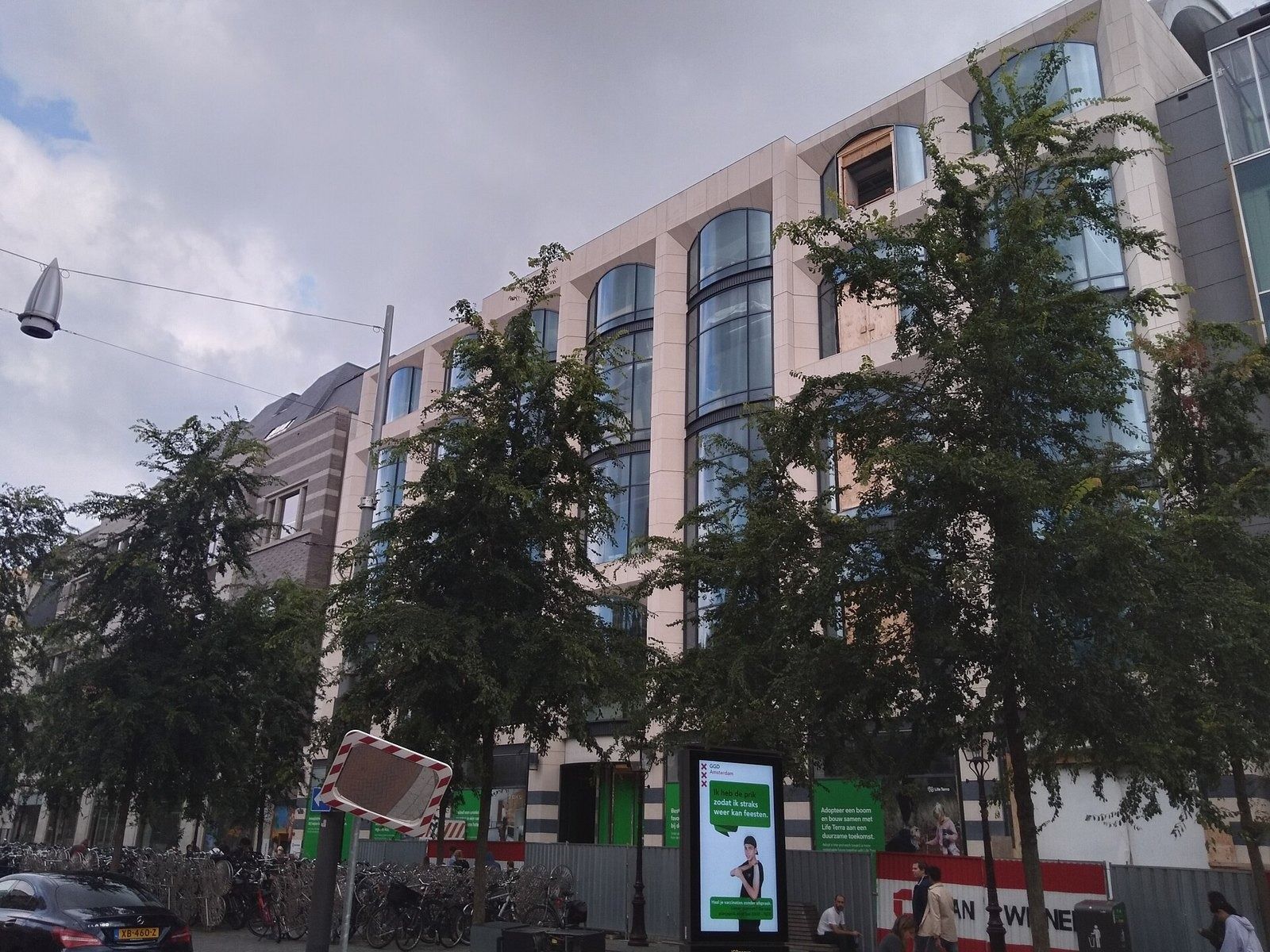 Adyen: Light stone building with large windows behind street trees
