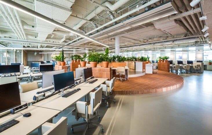 Adyen: Rows of desks with monitors beside a curved wooden platform with plants