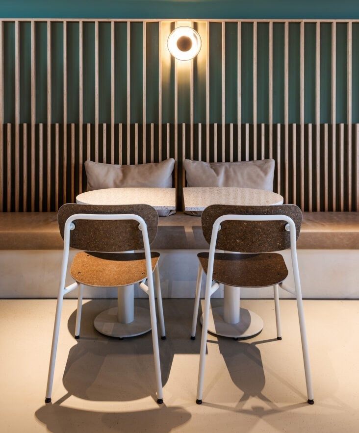 Adyen: Two chairs at a table in front of an upholstered bench and slatted wall