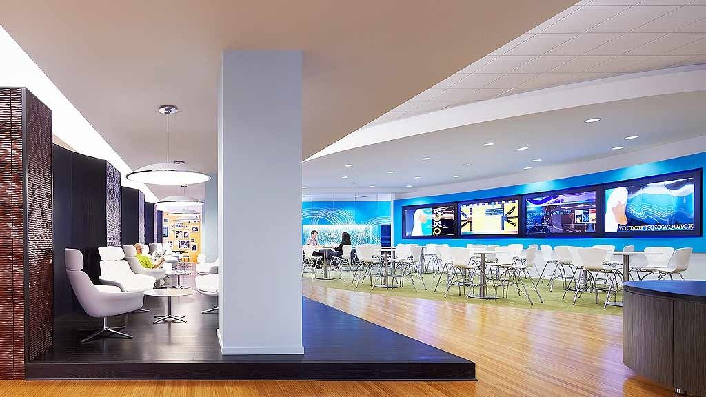 Aflac: A multi-purpose café with wood floors, lounge chairs and a long row of screens