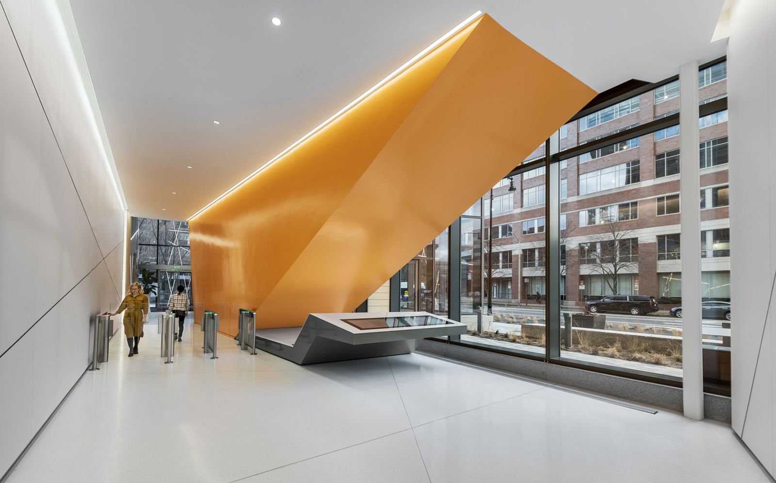 A lobby with a huge orange angled form above the turnstiles