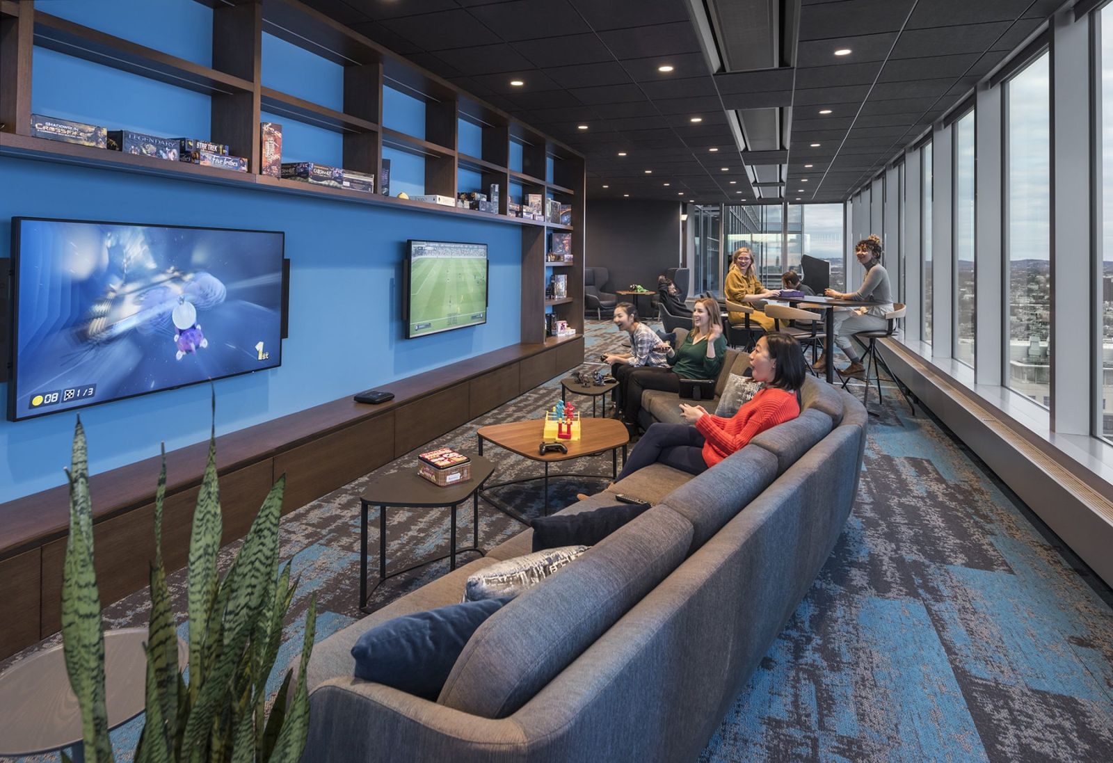 Akamai: A long lounge with sofas, screens and city views