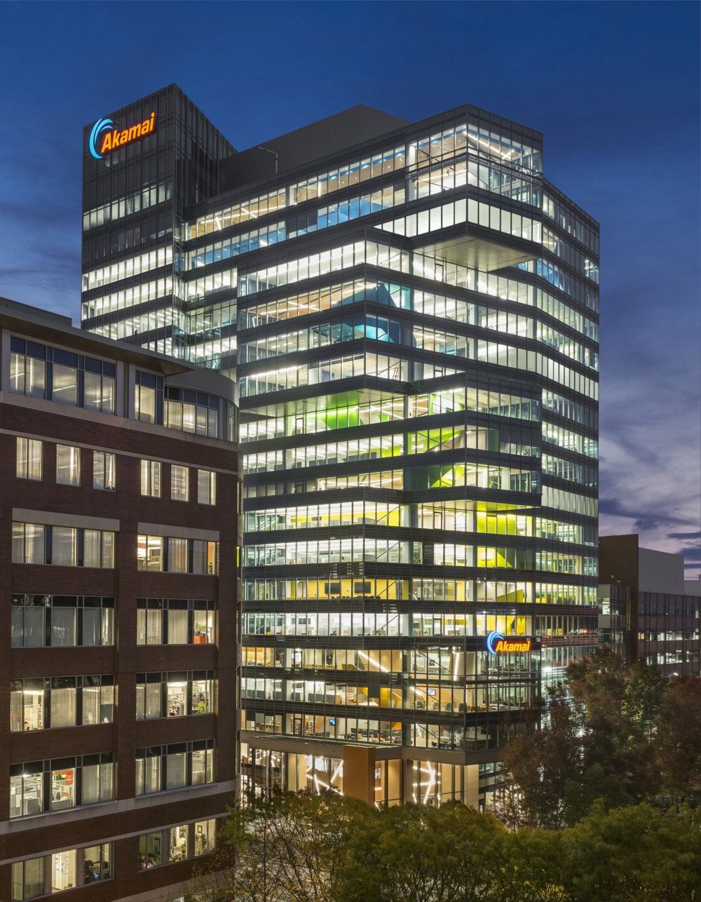 Akamai: Glass office tower with the Akamai name lit at dusk