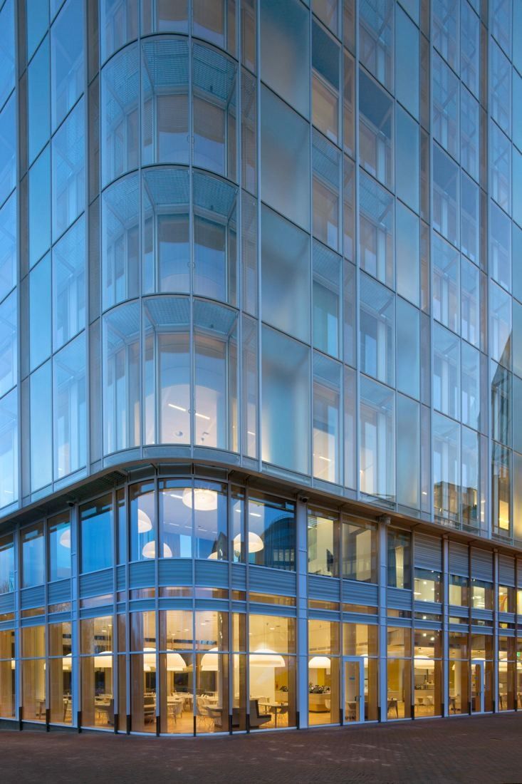 AkzoNobel: Close view of curved layered glass façade above a lit ground floor