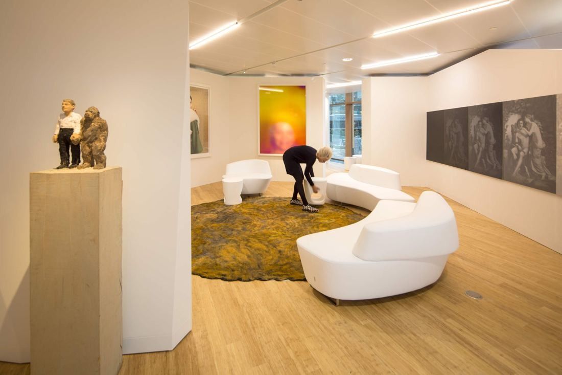 AkzoNobel: Gallery room with a sculpture on a plinth, curved white sofa, green rug and artworks on the walls