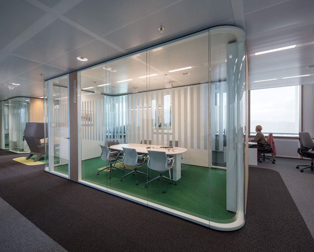 AkzoNobel: Glass meeting room with rounded corners and a green floor on an office floor