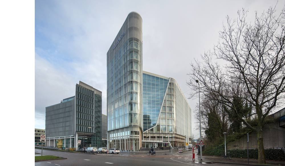 AkzoNobel: Glass office building with a rounded tower on an overcast day, seen across a street