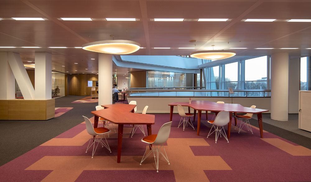 AkzoNobel: Office floor with red and pink carpet zones, tables and round ceiling lights