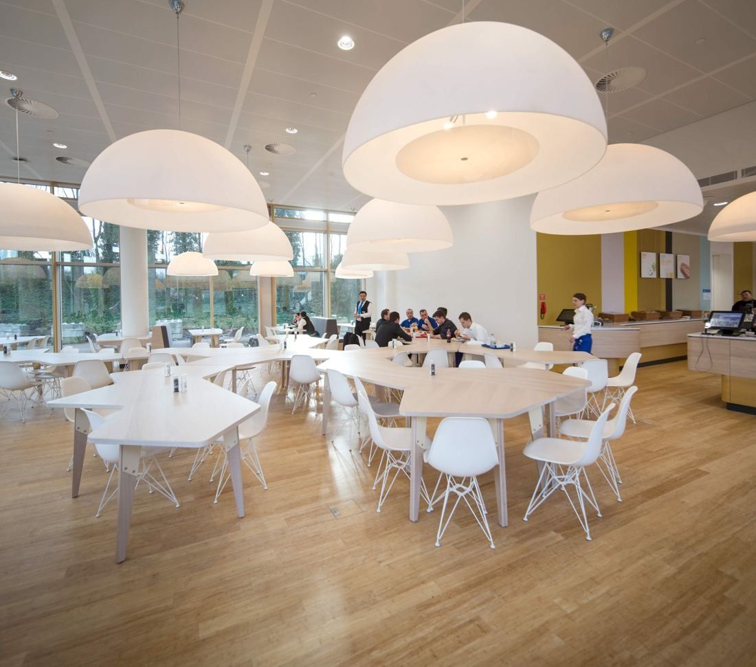 AkzoNobel: Restaurant with white chairs, light wood floor and large dome-shaped pendant lamps