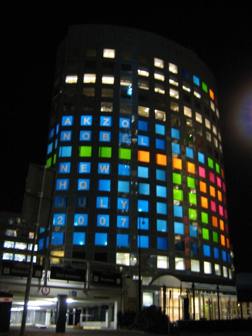 Round office tower at night with windows lit in many colours