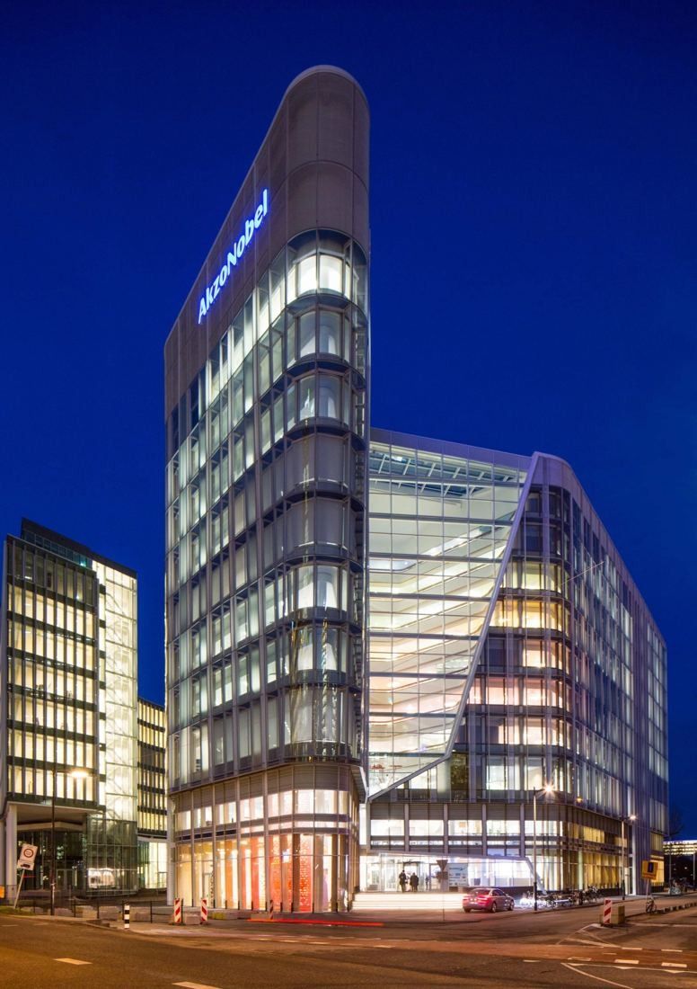 AkzoNobel: Rounded glass tower corner lit at night against a deep blue sky
