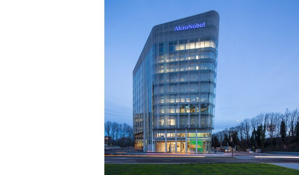 AkzoNobel: Rounded glass tower with the AkzoNobel name at the top, seen at dusk