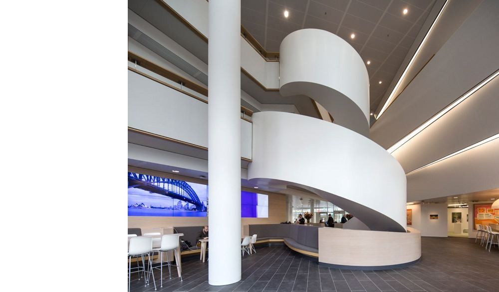 AkzoNobel: White spiral staircase rising from a lobby with a column and high tables