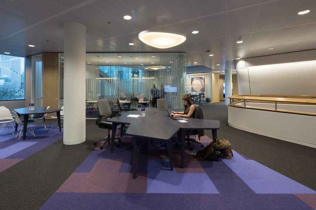AkzoNobel: Work area with purple and lilac carpet, dark shared desk and glass meeting rooms behind