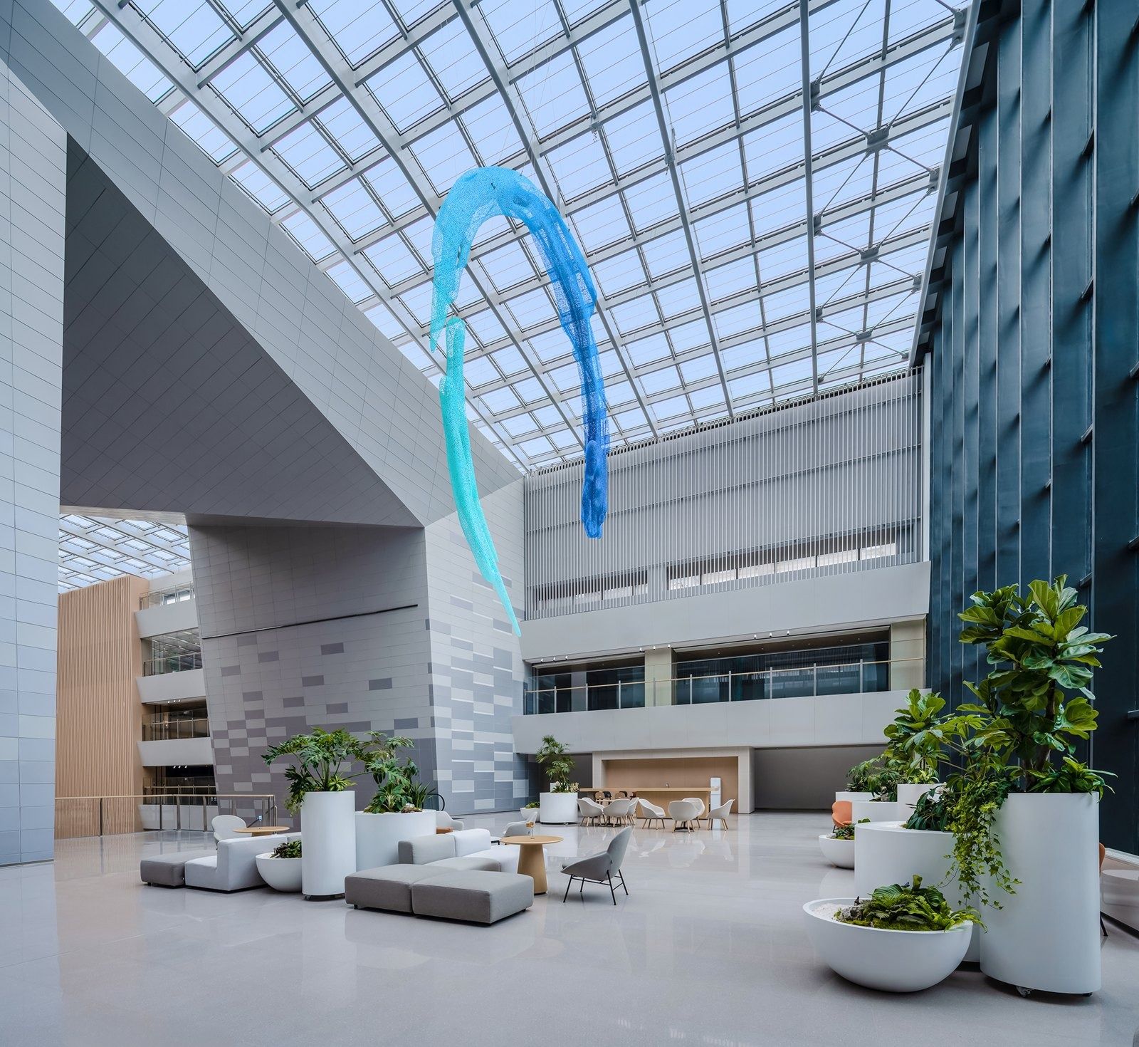 Alibaba Group: Glass-roofed hall with a blue sculpture and lounge chairs
