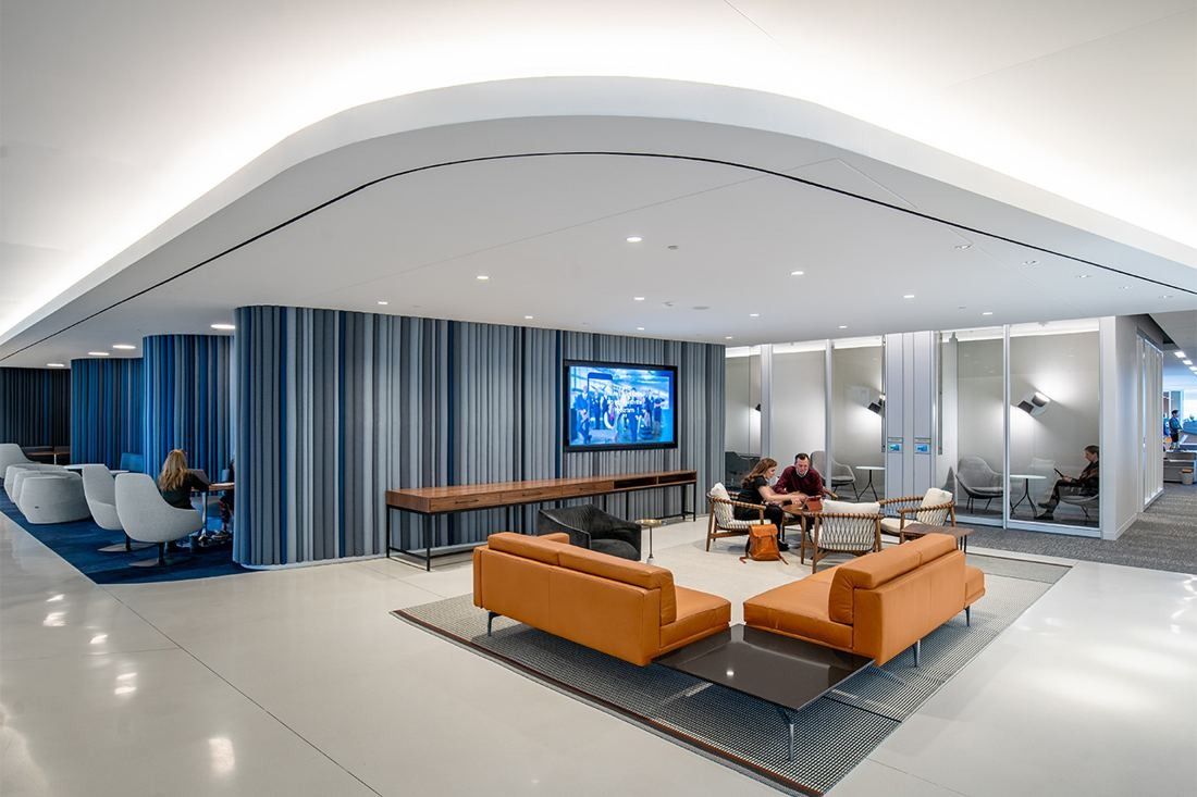 American Airlines: Lounge with tan sofas, a wall screen and curtained walls