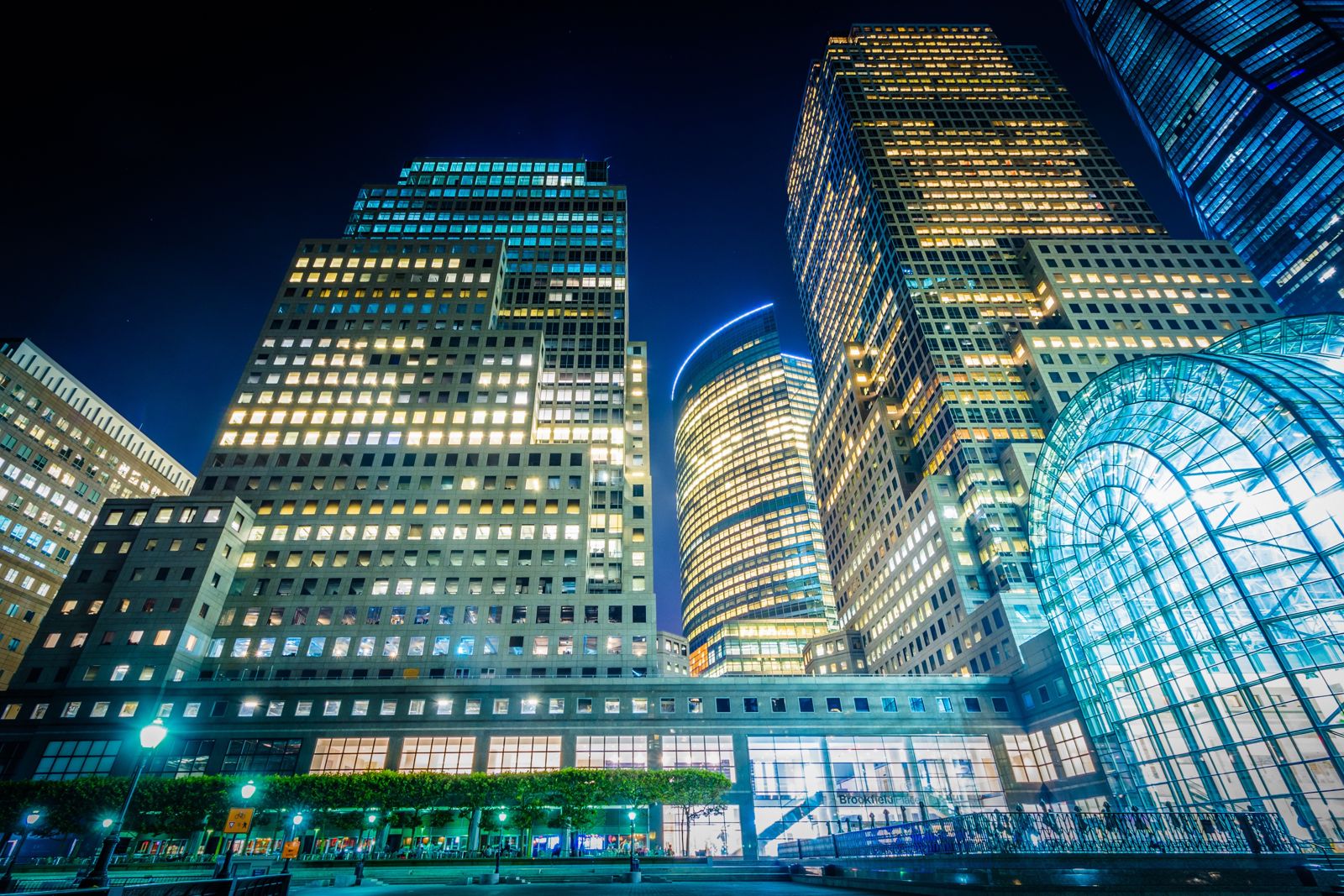 Lit office towers and a glass-vaulted atrium at night