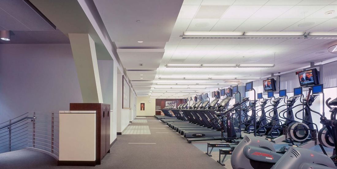 Amgen: Long fitness room lined with cardio machines and wall-mounted screens