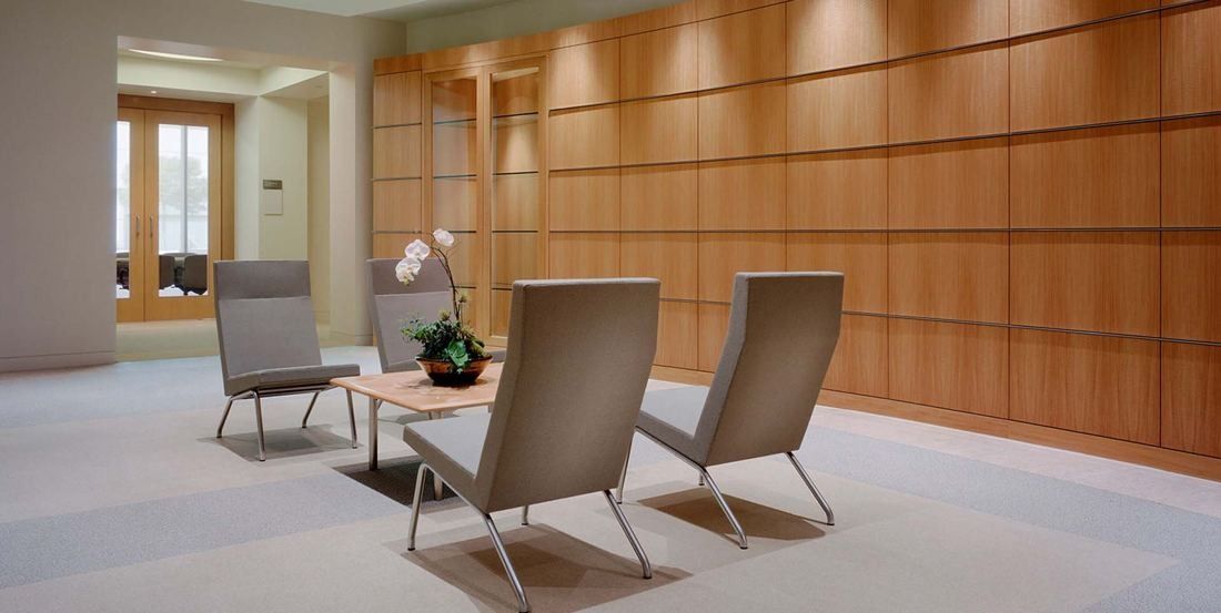 Amgen: Seating area with grey lounge chairs in front of a wood-panelled wall