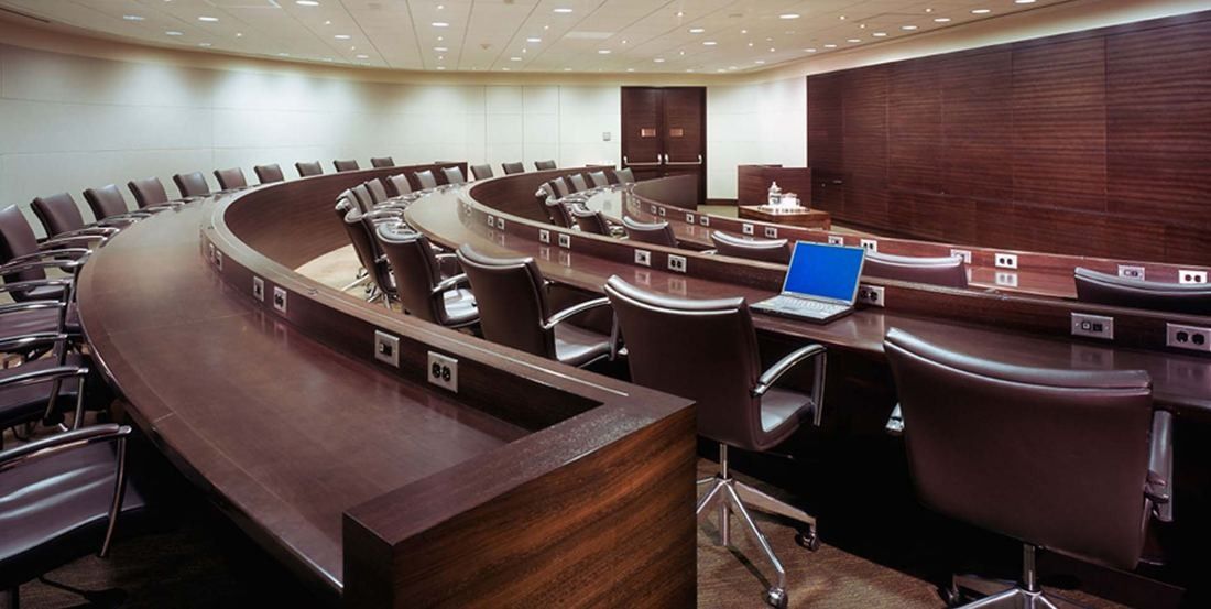Amgen: Tiered auditorium with curved wooden desks and rows of leather chairs