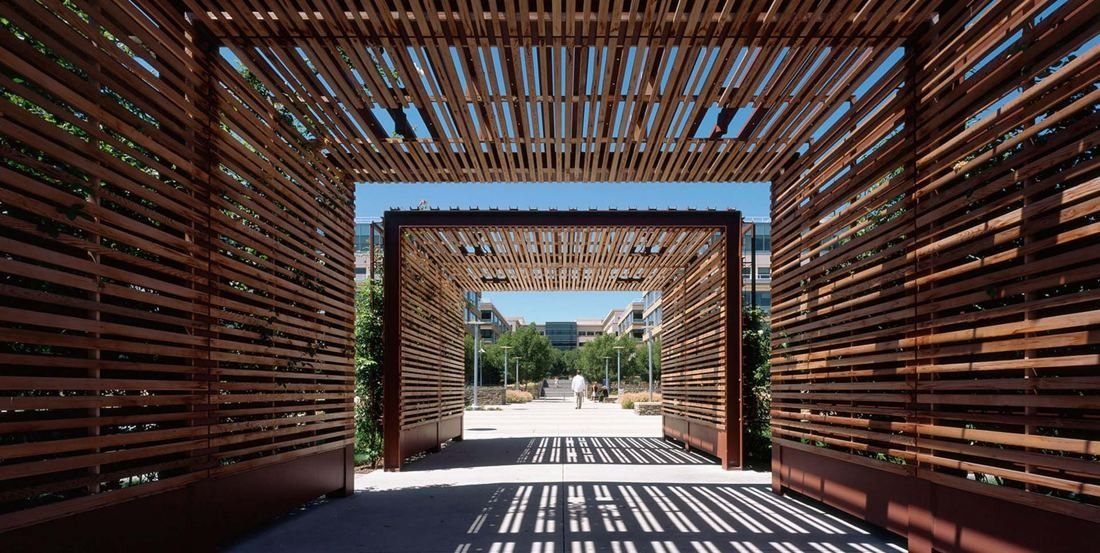 Amgen: Walk-through passage framed by slatted wooden screens, opening onto a sunny plaza