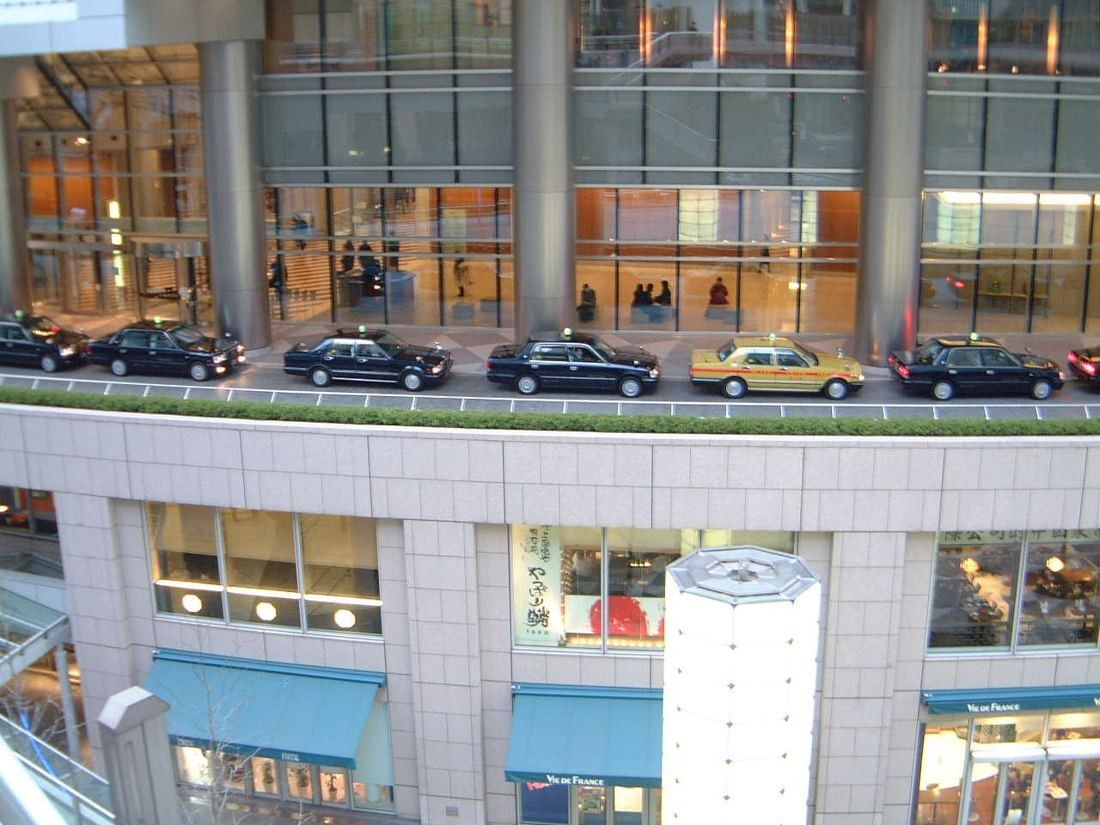 ANA: Glazed ground floor with taxis lined up above a sunken level of shops
