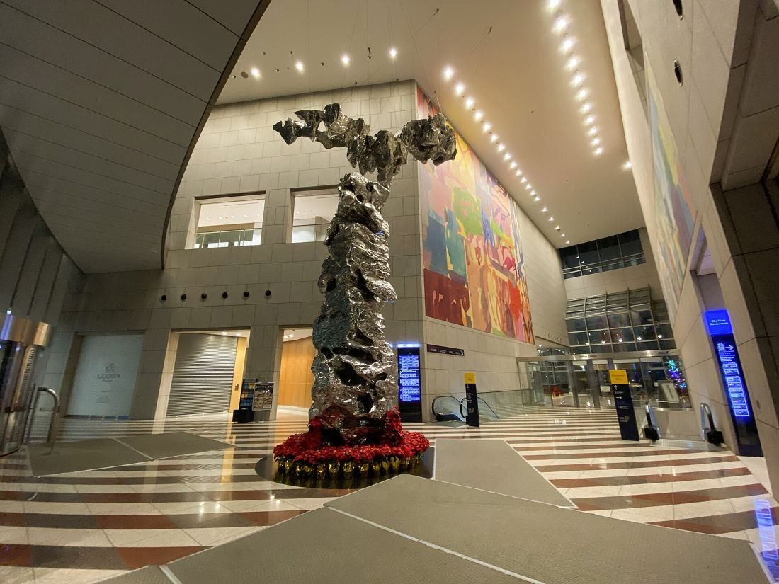 ANA: Tall office lobby with a large silver sculpture, a colourful wall mural and striped stone floor