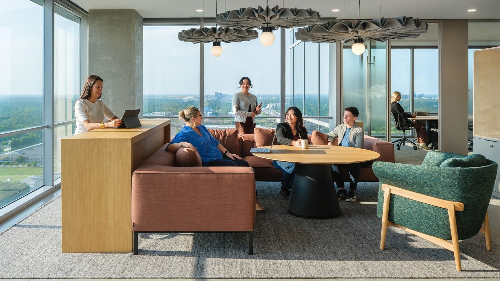 APA Corporation: A corner lounge with sofas, a round table and floor-to-ceiling windows