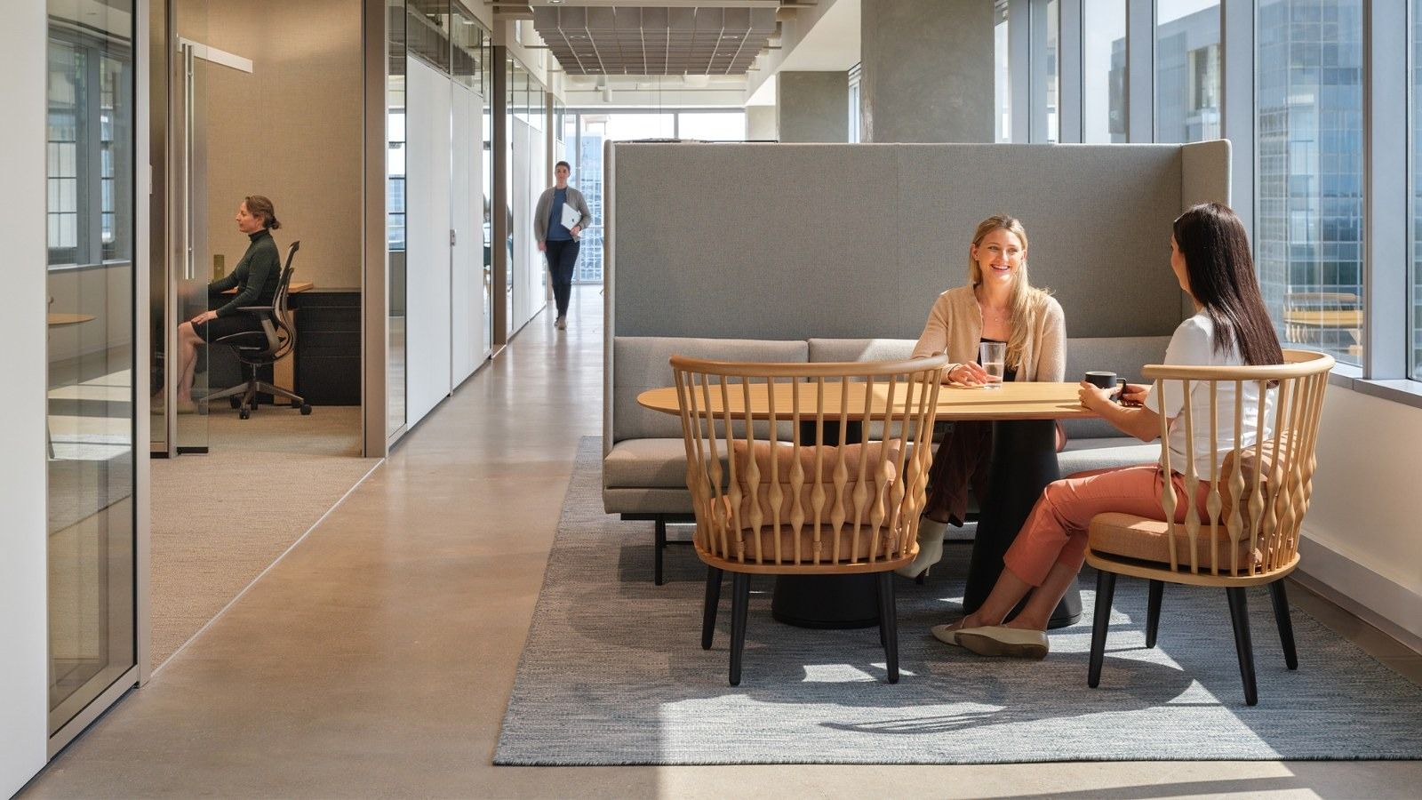 APA Corporation: A corridor with glass offices and a booth with rattan chairs