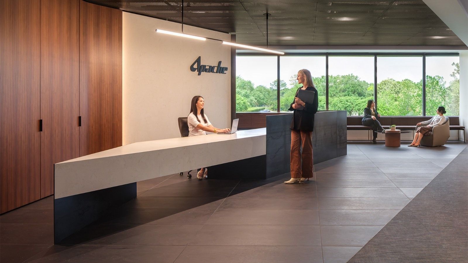 APA Corporation: A reception with a white desk, wood walls and the Apache name