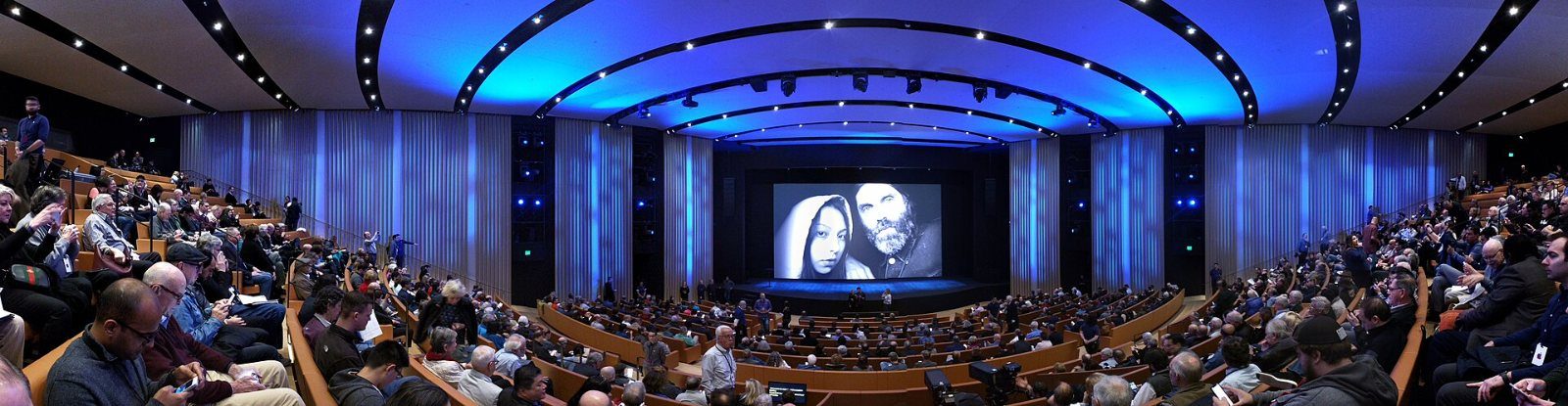 Apple: Wide view of a dark auditorium lit in blue