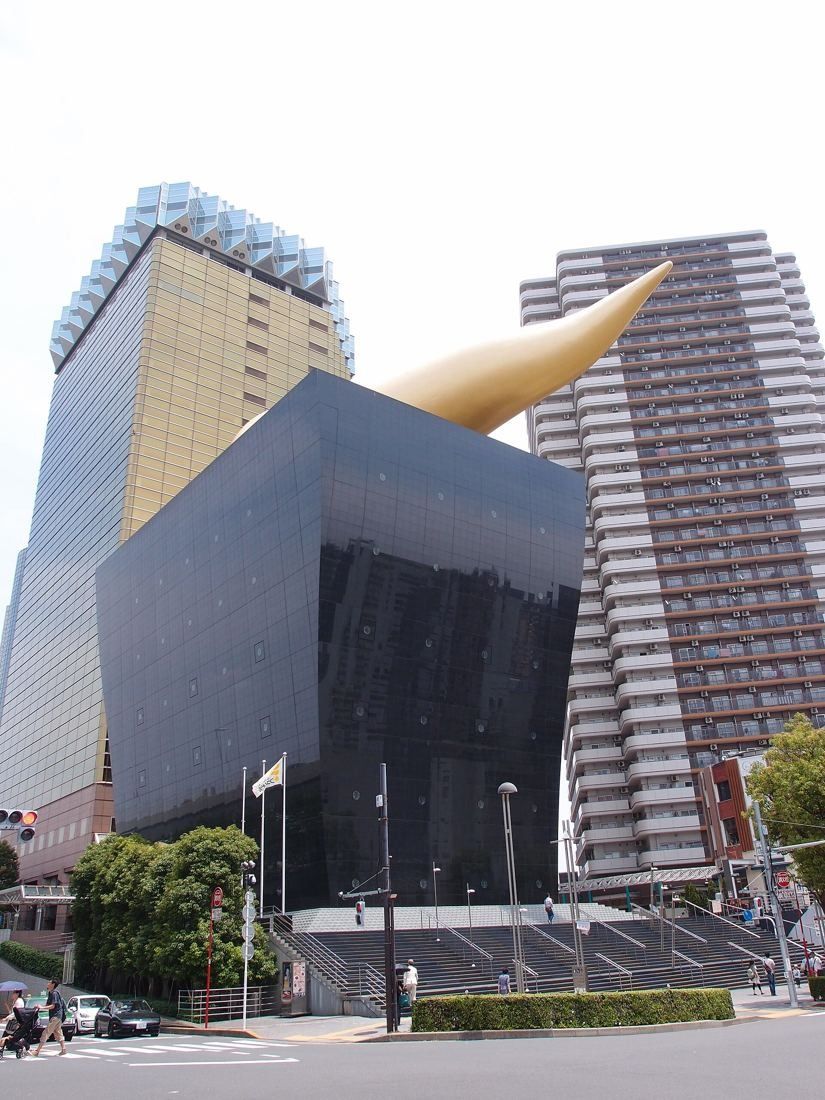 Asahi Group Holdings: Black hall with the golden flame, the gold tower behind and a residential tower to the side