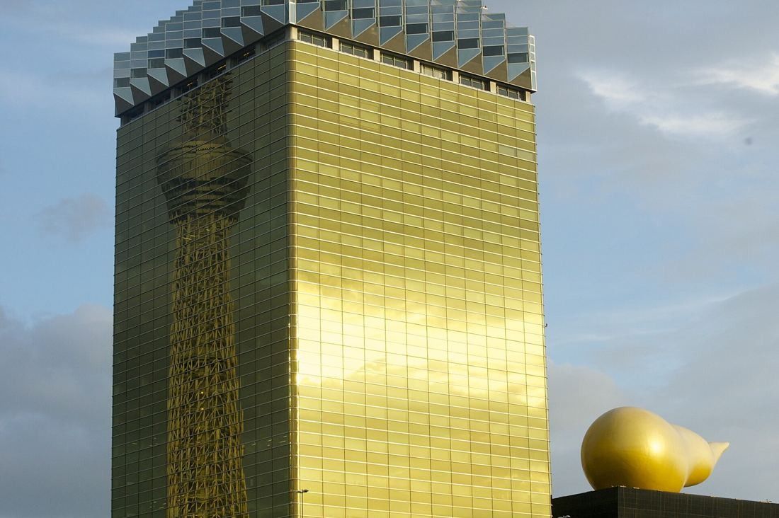 Asahi Group Holdings: Close view of the gold glass facade with Tokyo Skytree reflected in it and the golden flame at the corner