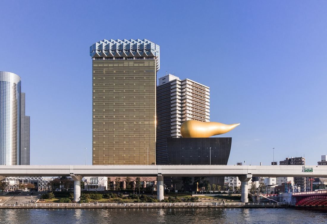 Asahi Group Holdings: Gold tower, black hall and golden flame across the Sumida River under a clear sky