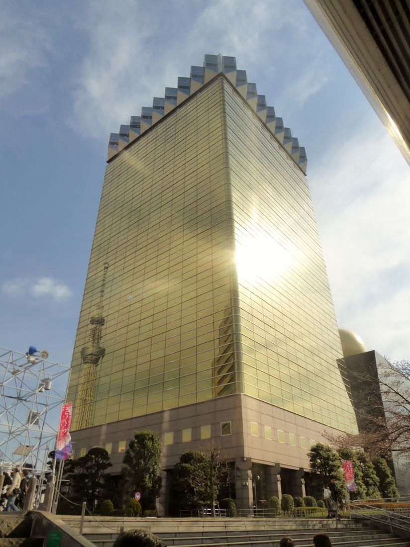 Asahi Group Holdings: Gold tower glowing in sunlight, seen from below