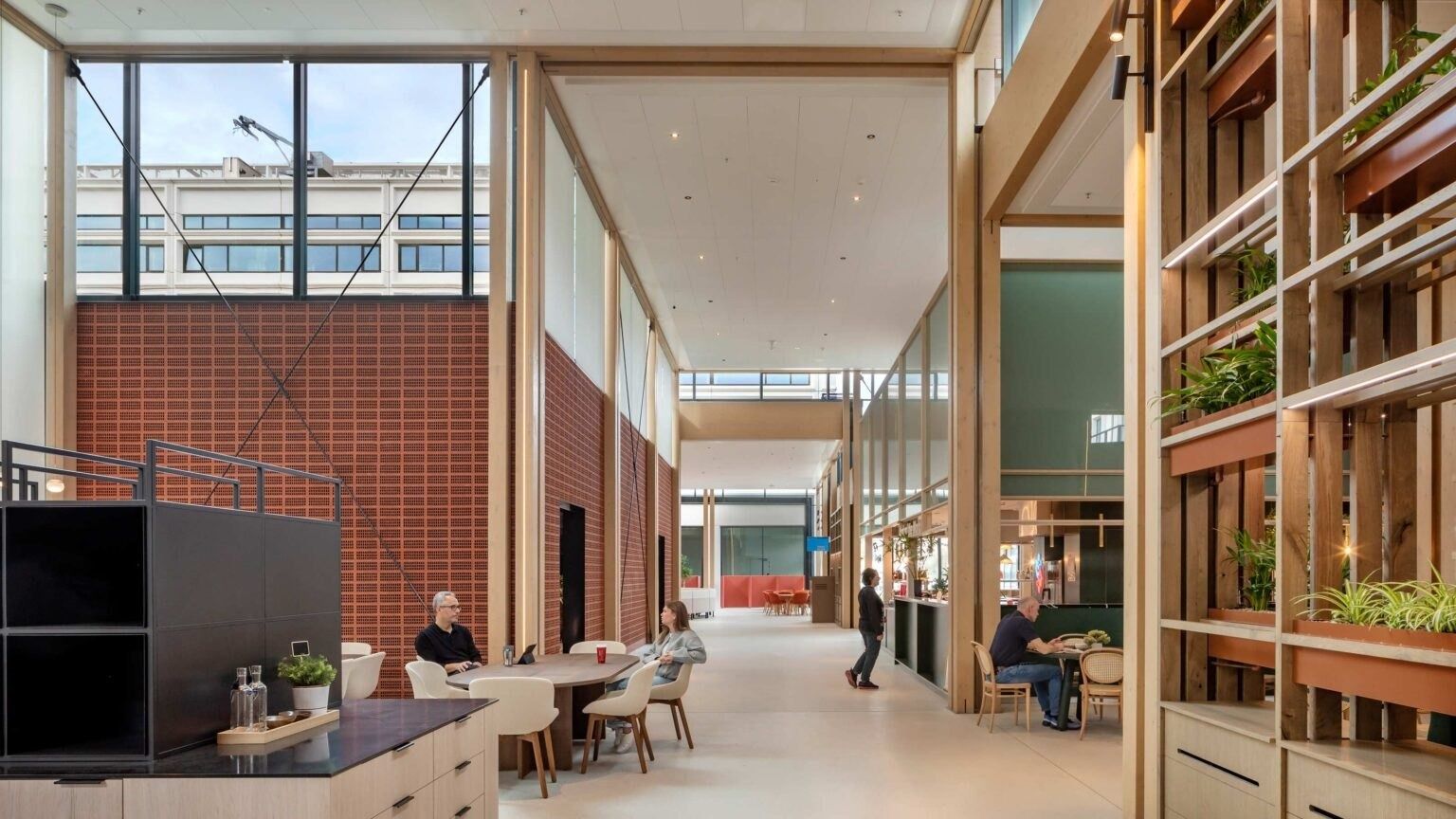 A long interior street with wood shelving, plants and brick walls